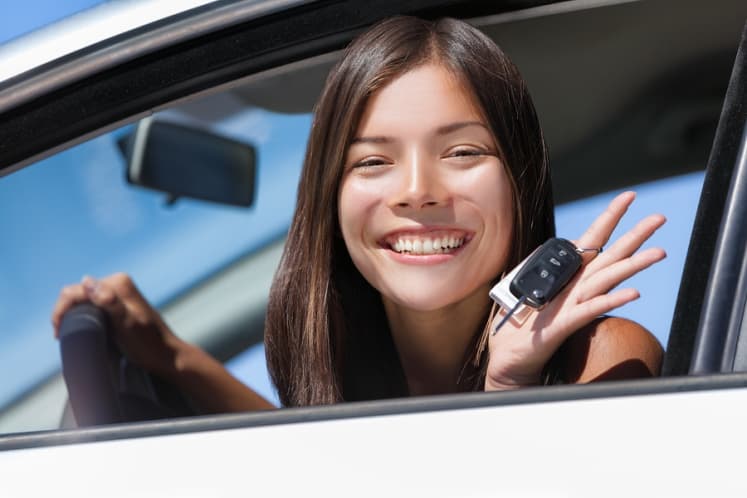 Teen driver holding car keys and smiling